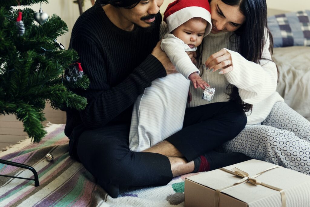 mother, father, and baby at christmas tree