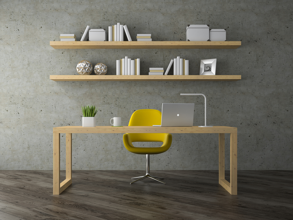 Wood desk with bright yellow chair and concrete wall with books