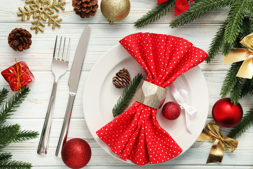 Red and white napkin on white dishes with ornaments around it