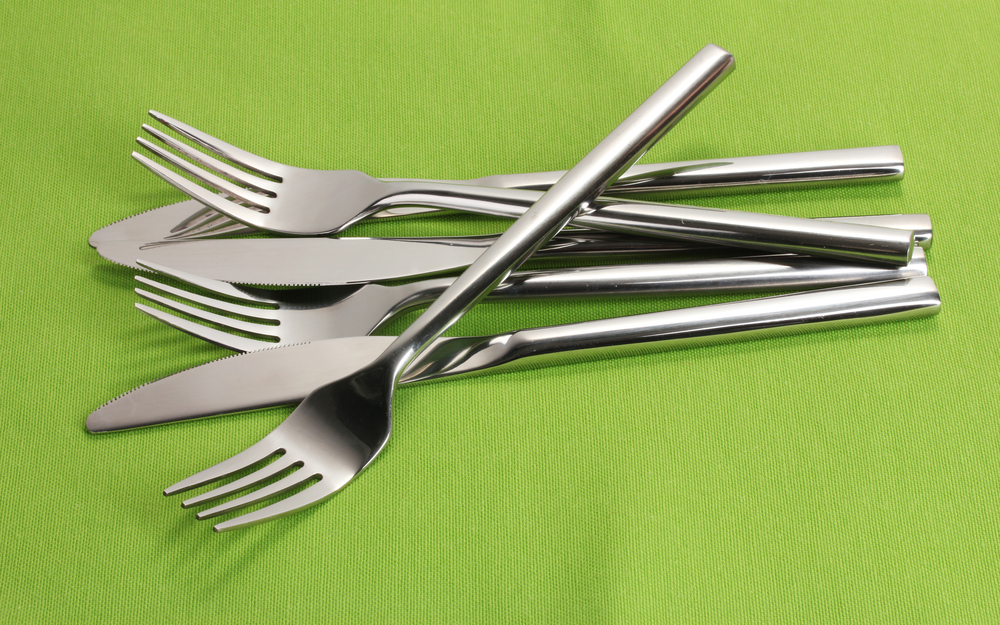 Shiny forks and knives on a lime green background