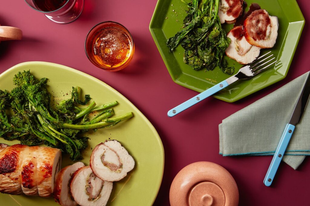 green plates, blue handled flatware on red table