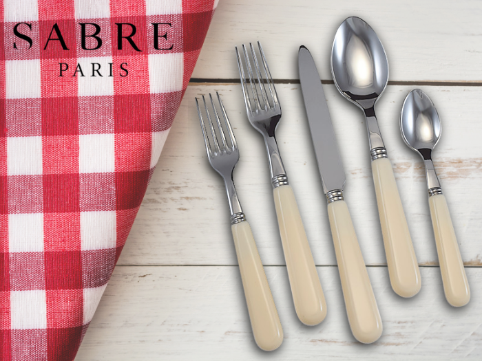 Wood handled flatware next to red and white napkin all on a wood tabletop