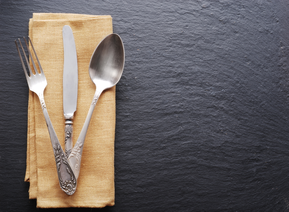 Sterling flatware on beige napkin place on dark black table