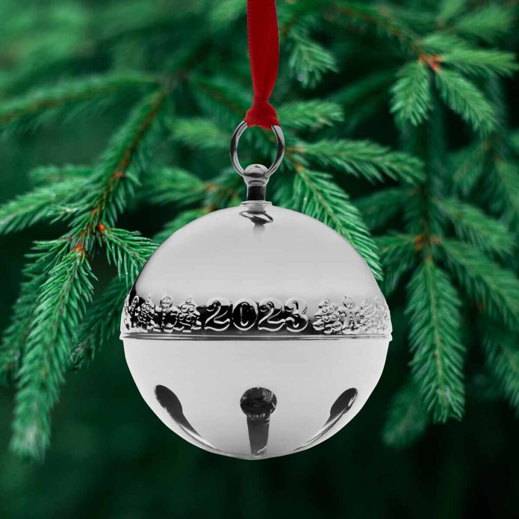 Silver Sleigh Bell ornement hanging from ribbon on tree