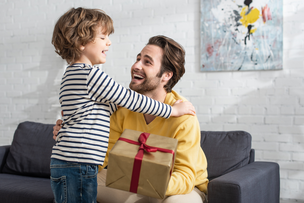 boy giving his father a present, both smiling