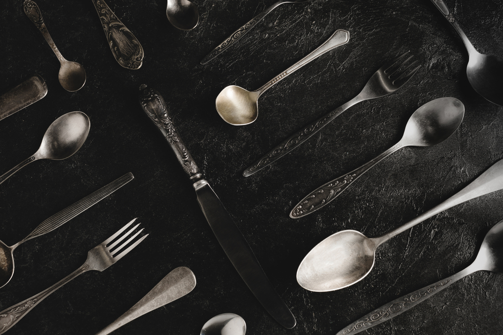 spoons, forks, and knives placed on a dark background